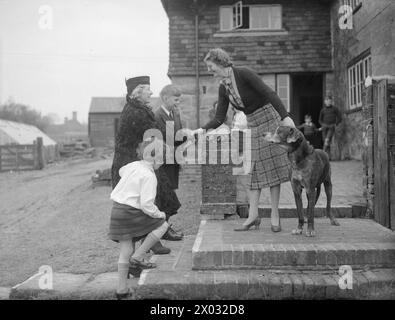 LES CARTER EN TEMPS DE GUERRE : LA VIE QUOTIDIENNE D'Une FAMILLE BRITANNIQUE SUR LE FRONT INTÉRIEUR, ANGLETERRE, C 1940 - Mme Cluton, une «mère adoptive» de nombreuses personnes évacuées, accueille Mme carter dans sa maison de Hayward's Heath. Les enfants de Mme carter, Michael et Angela, vivent avec Mme Cluton à Hayward's Heath depuis leur évacuation de Londres. En arrière-plan, plusieurs autres évacués, également logés avec Mme Cluton, peuvent être vus Banque D'Images