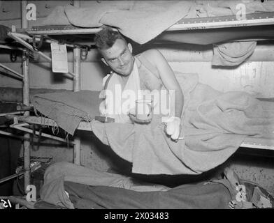 AVEC UN NAVIRE DE DÉBARQUEMENT DE CHAR D'HÔPITAL. LES 10 ET 11 AOÛT 1944, COURSSELLES, FRANCE, AVEC LST 428. SPÉCIALEMENT AMÉNAGÉ POUR CETTE TÂCHE, LE LST 428 AIDE À TRANSPORTER LES VICTIMES, Y COMPRIS LES BLESSÉS ENNEMIS, DE LA ZONE DE BATAILLE AU ROYAUME-UNI. - Soldat Une McLay, d'Athabaska, Alberta, prenant une tasse de thé de bienvenue à bord du LST 428 Banque D'Images