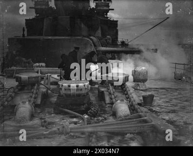 CONVOI EN RUSSIE, AVEC ESCORTE DE CROISEUR BRITANNIQUE SUR LA LIGNE DE VIE ARCTIQUE. DÉCEMBRE 1941, À BORD DU CROISEUR HMS SHEFFIELD. - Avec un jet de vapeur un groupe de stokers libère le cabestan de la glace épaisse Banque D'Images