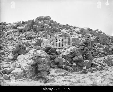 LES MARINS S'ENTRAÎNENT COMME SAPEURS POUR FRAPPER LE TERRITOIRE OCCUPÉ ENNEMI. 1942, HVALFJORD, ISLANDE. LES MARINS QUI SUIVENT UNE FORMATION POUR LES TRAVAUX DE DÉMOLITION, OÙ ON LEUR MONTRE COMMENT PRÉPARER DES CHARGES ET DES DÉTONATEURS POUR LA DESTRUCTION DES BIENS ET DES DÉFENSES ENNEMIS COMME ILS LE FERAIENT LORS D'UN DÉBARQUEMENT EN TERRITOIRE OCCUPÉ PAR L'ENNEMI. - Des notations couvrant leurs camarades qui transportent des câbles, des fils téléphoniques et des explosifs à un objectif choisi Banque D'Images