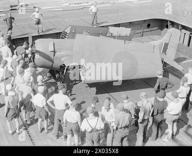 LES ENVAHISSEURS DU SUD DE LA FRANCE SE PRÉPARENT. LE 7 AOÛT 1944, À BORD DU PORTE-AVIONS D'ESCORTE BRITANNIQUE HMS PURSUER, QUI FAISAIT PARTIE DE LA FORCE ALLIÉE QUI PRIT PART AU DÉBARQUEMENT DANS LE SUD DE LA FRANCE LE 15 AOÛT 1944. LES PRÉPARATIFS SONT FAITS POUR L'ASSAUT, ET LES NAVIRES DE LA FLOTTE SE METTENT EN ROUTE POUR L'ACTION. - Un Wildcat en train d'être rangé pendant qu'un groupe de pont d'envol renforcé se tient debout pour le manipuler Banque D'Images