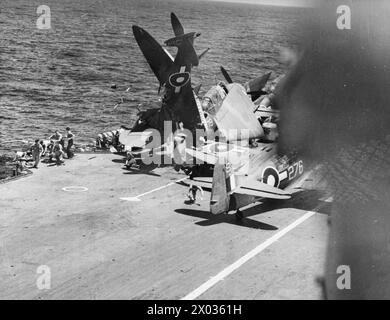 LA NAVY V LES JAPONAIS. JUIN 1945, DANS LE PACIFIQUE LORS D'UNE ATTAQUE D'AVIONS JAPONAIS CONTRE DES PORTE-AVIONS DE LA FLOTTE BRITANNIQUE DU PACIFIQUE LORSQUE CINQ AVIONS ENNEMIS ONT ÉTÉ ABATTUS EN MER. - Image de Split-seconde des cotes de manutention de pont comme ils «sortent de dessous» quand un avion Seafire s'écrase dans un avion stationné sur le pont d'envol Banque D'Images