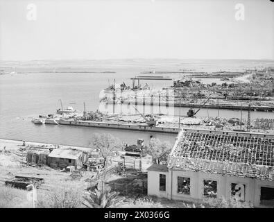 COMMENT LES FORCES AÉRIENNES ALLIÉES ONT MITRAILLÉ FERRYVILLE. 13 MAI 1943, FERRYVILLE, CHANTIER NAVAL FRANÇAIS, PRÈS DE BIZERTE. LE PORT DE FERRYVILLE A OBTENU SA PART DU BLITZ ALLIÉ PRESQUE SANS ESCALE SUR LES POINTS D’APPROVISIONNEMENT DE L’AXE QUI ONT PRÉCÉDÉ LA DÉFAITE TOTALE DE L’ALLEMAGNE ET DE L’ITALIE EN AFRIQUE. - Rejoindre Ferryville, montrant les dégâts causés par les raids aériens alliés. Sur la gauche de l'image, juste à côté de la jetée, se trouvent les restes d'un navire de munitions italien de 6 000 à 8 000 tonnes qui a reçu un coup direct d'une bombe. L'explosion a causé d'importants dommages au chantier naval, et des parties du navire ont été ramassées pas moins de Banque D'Images