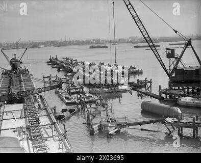 MULBERRY HARBOUR. AVRIL 1944, SOUTHAMPTON. DEUX IMMENSES PORTS PRÉFABRIQUÉS UTILISÉS SUR LA CÔTE NORMANDE APRÈS L'INVASION ONT ÉTÉ CONSTRUITS EN PLUSIEURS PARTIES, REMORQUÉS À TRAVERS LE CHENAL ET DÉPOSÉS. LES PORTS SE COMPOSAIENT D'ÉNORMES CAISSONS DE BÉTON DÉPOSÉS POUR FORMER LE BRISE-LAMES, DE JETÉES FLOTTANTES ET DE PIERHEADS, AINSI QUE DE 15 NAVIRES OBSOLÈTES UTILISÉS COMME BRAS PORTUAIRE PRÉLIMINAIRE. - Assemblage des composants des jetées ou des chaussées (baleines) Banque D'Images