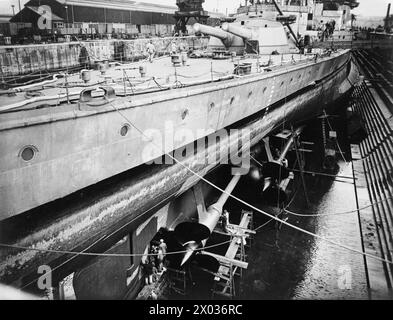 Des ouvriers effectuent la maintenance du gouvernail et des hélices du HMS Repulse lors de son réaménagement en cale sèche, 1940. Banque D'Images