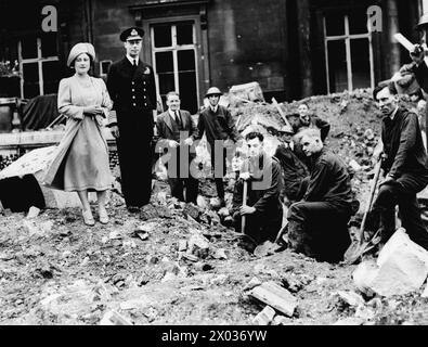 LE BLITZ DE LONDRES 1940 - le roi George VI et la reine Elizabeth debout avec des ouvriers, tout en inspectant les dégâts causés par les bombes au palais de Buckingham Banque D'Images