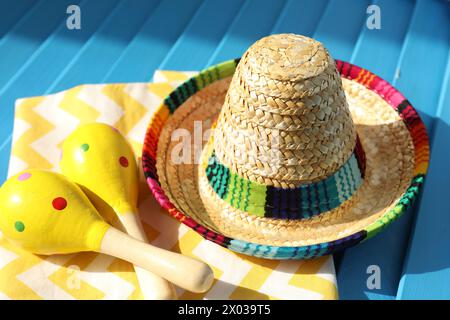 Chapeau sombrero mexicain, serviette et maracas sur surface en bois bleu Banque D'Images