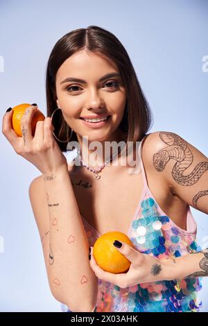 Une jeune femme aux cheveux bruns tenant une orange dans une main et une tranche de fruit dans l'autre. Banque D'Images