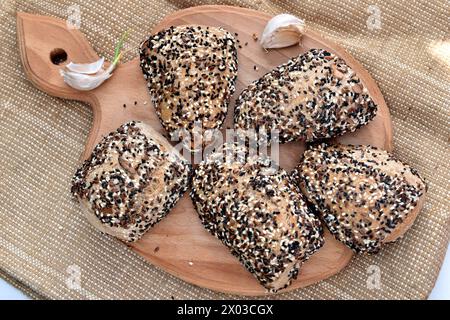 Pain fait maison saupoudré de graines de lin et de petites graines de cumin se trouve sur une planche, vue de dessus. Banque D'Images