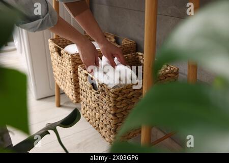 Femme mettant des serviettes dans le panier de rangement à l'intérieur, gros plan Banque D'Images