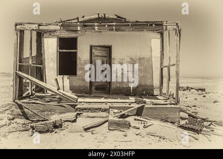 Porte d'une maison de mineur abandonnée, préservée par l'air sec du désert, à la mine Bogenfels dans la zone interdite en Namibie. Sépia. Banque D'Images