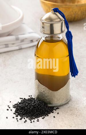 Bouteille unique avec de l'huile de nigelle et un tas de graines de nigelle dans le hammam gros plan Banque D'Images