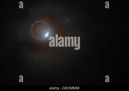 Van Wert, Ohio, États-Unis. 8 avril 2024. Une éclipse solaire totale, vue du nord-ouest de l'Ohio. Les protubérances rougeâtres qui se projettent autour de l'ombre de la lune sont des taches de plasma en éruption du plus profond du soleil. Le flash de lumière en bas à droite lorsque le soleil commence à émerger de l'ombre de la lune est appelé l'anneau de diamant. Crédit : Jim West/Alamy Live News Banque D'Images