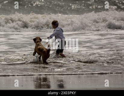 Bournemouth Dorset 9 avril 2024 Météo britannique ; les visiteurs apprécient le soleil printanier malgré les vents violents et la grande houle des tempêtes nocturnes. Chien et propriétaire appréciant la plage crédit : Ian Davidson/Alamy Live News Banque D'Images