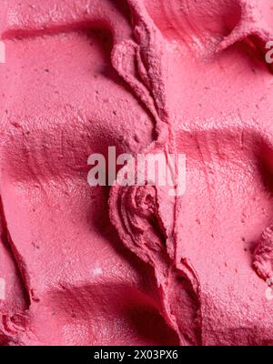 Glace à saveur de fraise surgelée - détail plein cadre. Gros plan sur une surface rose de crème glacée. Banque D'Images