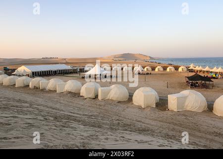 Tentes au camp du désert QIA à la mer intérieure dans le golfe Persique au coucher du soleil. Moyen-Orient, péninsule arabique. La mer intérieure est une destination touristique majeure. Qatar Banque D'Images