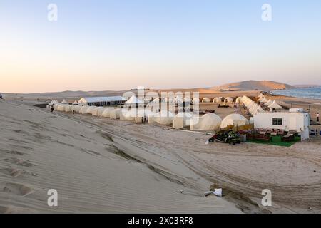 Tentes au camp du désert QIA à la mer intérieure dans le golfe Persique au coucher du soleil. Moyen-Orient, péninsule arabique. La mer intérieure est une destination touristique majeure. Qatar Banque D'Images