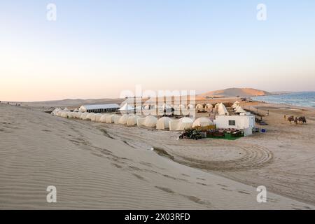 Tentes au camp du désert QIA à la mer intérieure dans le golfe Persique au coucher du soleil. Moyen-Orient, péninsule arabique. La mer intérieure est une destination touristique majeure, Qatar Banque D'Images