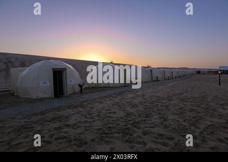 Tentes au camp du désert QIA à la mer intérieure dans le golfe Persique au coucher du soleil. Moyen-Orient, péninsule arabique. La mer intérieure est une destination touristique majeure Banque D'Images