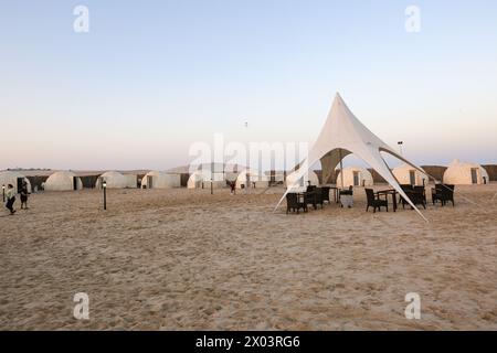 Tentes au camp du désert QIA à la mer intérieure dans le golfe Persique au coucher du soleil. Moyen-Orient, péninsule arabique. La mer intérieure est une destination touristique majeure. Banque D'Images