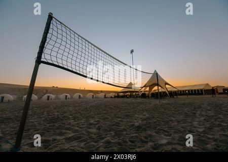 Silhouette d'un filet de volley-ball et coucher de soleil sur la plage dans une station tropicale au Qatar Banque D'Images