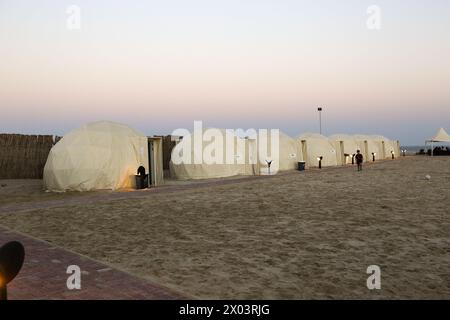 Tentes au camp du désert QIA à la mer intérieure dans le golfe Persique au coucher du soleil. Moyen-Orient, péninsule arabique. La mer intérieure est une destination touristique majeure, Qatar Banque D'Images