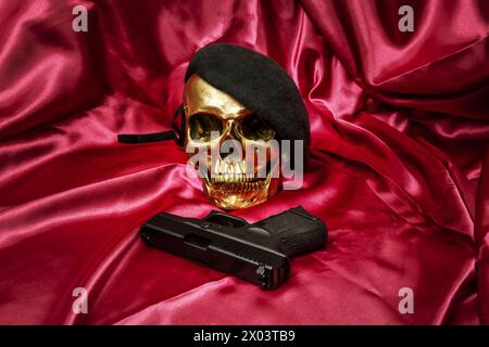 un crâne doré avec une âme de béret vert avec des voeux de guerre sur un tissu rouge sang Banque D'Images