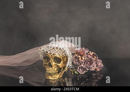 Un crâne doré avec un chapeau et un bouquet de fleurs dans une pièce enfumée Banque D'Images