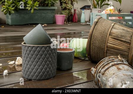 Pots de fleurs vides de toutes sortes à côté de diverses plantes sur le plancher en bois avec des pots de fleurs en métal rouillé au premier plan Banque D'Images