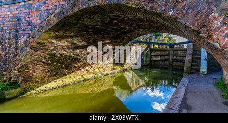 Une vue sous une passerelle vers les portes de l'écluse sur le Grand Union canal à Aylestone Meadows, Leicester, Royaume-Uni au printemps Banque D'Images