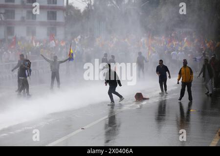 Les monarchistes affrontent la police au Népal les manifestants pro-monarchiques népalais trempent dans l'eau tirée du canon à eau de la police népalaise après avoir tenté de marcher plus loin dans la zone interdite près de Singha Durbar, capitale administrative de la nation himalayenne le 9 avril 2024. Des milliers de pro-monarchistes et de cadres du parti Rastriya Prajatantra RPP ont frappé les rues de Katmandou en affrontant à nouveau le personnel de sécurité alors qu'ils tentaient de pénétrer dans la zone d'accès restreint. Le RPP, un parti de droite pro-monarque, a dirigé et appelé à protester pour réclamer la restauration de la monarchie et du Royaume hindou. Banque D'Images