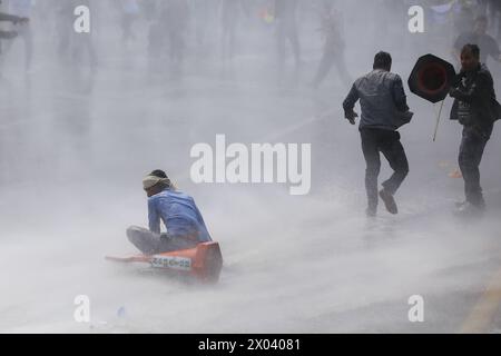 Les monarchistes affrontent la police au Népal Un manifestant pro-monarchie népalais tombe sur le sol après avoir été touché par de l'eau jaillissante tirée du canon à eau de la police népalaise alors qu'ils s'affrontent après une brèche de sécurité qui a permis aux manifestants d'entrer dans la zone interdite près de Singha Durbar, capitale administrative de la nation himalayenne le 9 avril 2024. Des milliers de pro-monarchistes et de cadres du parti Rastriya Prajatantra RPP ont frappé les rues de Katmandou en affrontant à nouveau le personnel de sécurité alors qu'ils tentaient de pénétrer dans la zone d'accès restreint. RPP, un parti pro-monarque de droite a dirigé un Banque D'Images