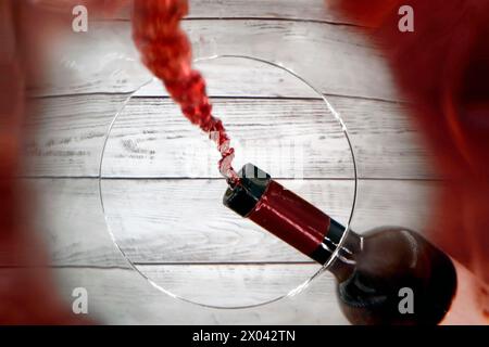 Un verre de vin est rempli de vin rouge à partir d'une bouteille de vin, perspective inhabituelle de l'intérieur du verre regardant jusqu'à la bouteille de vin qui verse Banque D'Images