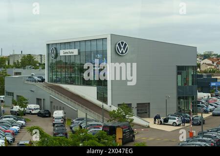 Lyon, France - 16 mai 2023 : la façade d'un bâtiment de concession Volkswagen avec des voitures garées et des clients à l'extérieur sous un ciel couvert. Banque D'Images