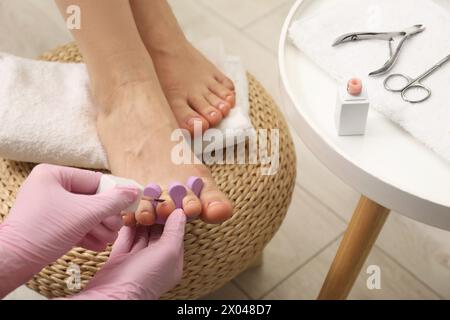 Pédicuriste professionnel peignant les ongles des orteils du client avec du vernis dans le salon de beauté, gros plan Banque D'Images