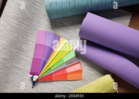 Différents rouleaux de papier peint, rouleaux et échantillons de palette de couleurs sur table, pose à plat Banque D'Images