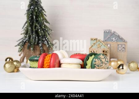 Macarons de Noël joliment décorés et décor festif sur table blanche Banque D'Images