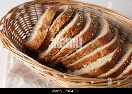 Tranches de pain frais fait maison dans un panier en osier sur la table, gros plan Banque D'Images