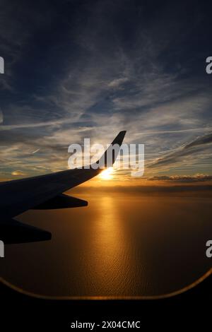 Avion volant au-dessus de la côte méditerranéenne d'Alicante , Espagne au coucher du soleil Banque D'Images