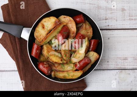 Pommes de terre frites avec de fines saucisses fumées sèches sur une table en bois blanc, vue de dessus Banque D'Images