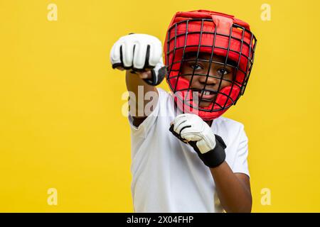 Petit garçon afro-américain combattant dans un casque de boxe de protection et des gants Banque D'Images