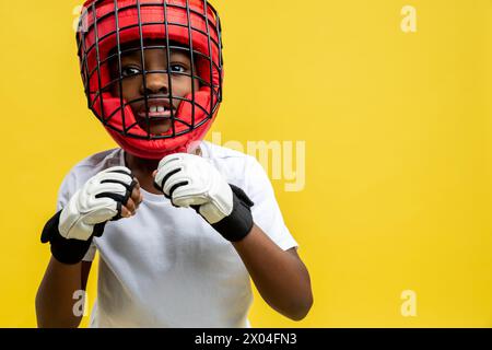 Petit garçon afro-américain combattant dans un casque de boxe de protection et des gants Banque D'Images