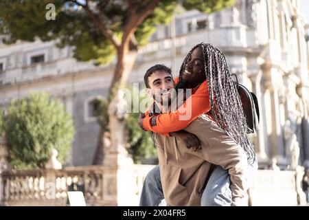 Couple interracial aime un tour de piggyback - joie et amour sur une rue ensoleillée de la ville - insouciant, partenariat aimant. Banque D'Images