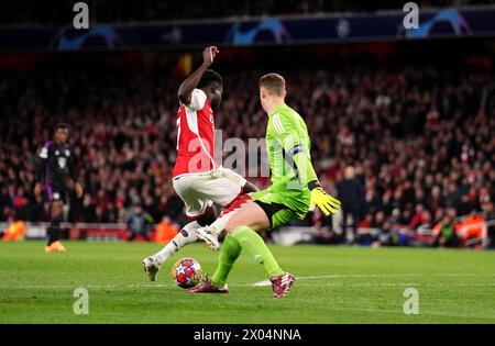 Bukayo Saka d'Arsenal tombe sous le défi du gardien de but Manuel Neuer du Bayern Munich lors du quart de finale de l'UEFA Champions League, match de première manche à l'Emirates Stadium de Londres. Date de la photo : mardi 9 avril 2024. Banque D'Images