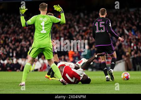 Bukayo Saka d'Arsenal tombe sous le défi du gardien de but Manuel Neuer du Bayern Munich lors du quart de finale de l'UEFA Champions League, match de première manche à l'Emirates Stadium de Londres. Date de la photo : mardi 9 avril 2024. Banque D'Images