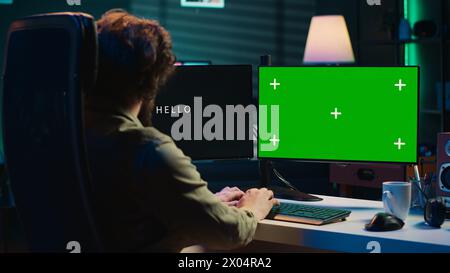 Programmeur mettant à jour l'algorithme d'intelligence artificielle à l'aide d'un PC à écran vert, ce qui le rend sensible. Spécialiste INFORMATIQUE programmant une IA auto-consciente avec ordinateur maquette, caméra A. Banque D'Images