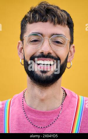 Gros plan souriant jeune homme caucasien joyeux avec des bretelles lgbt arc-en-ciel. Génération z. Banque D'Images