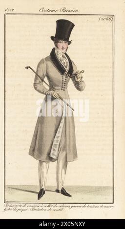 Dandy français en chapeau haut de gamme, manteau d'équitation peigné avec col en velours, boutons en nacre, gilet piqué, pantalon en coton, tenant une canne et monocle. Redingote de casimir a collet de velours, garnie de boutons de nacre, gilet de pique, pantalon de coutil. Gravure sur cuivre colorée à la main d’après une plaque mode de Louis Marie Lante du Journal des Dames et des modes de Pierre de la Mesangère, Magazine of Women and Fashion, Paris, 1822. Banque D'Images