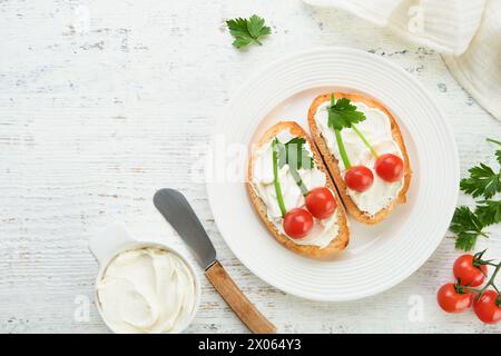 Toast drôle en forme de sandwich aux cerises mûres avec fromage à la crème, pain, tomate cerise, oignon et persil. Idée d'art alimentaire pour la nourriture des enfants. Pause créative Banque D'Images