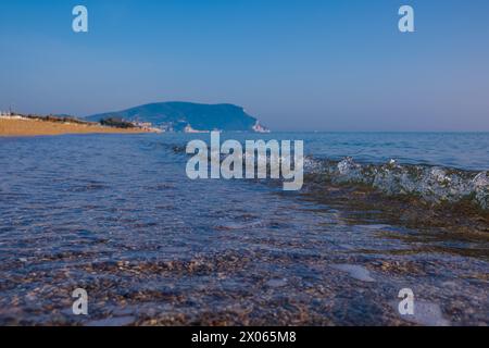 Belle mer calme par une journée ensoleillée. Gros plan sur le surf clair de mer. Une petite vague et de l'écume marine scintille au soleil. Banque D'Images